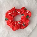 Close-up of red satin Christmas scrunchie with Santa and snowflake festive patterns - Red Santa Claus Style (Christmas Style 6)