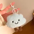 Close-up of a blue plush cloud charm featuring an embroidered smiley face and small brown legs - Keychain style / Blue