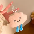Detail of pink plush cloud keychain with blue legs and embroidered smiling face - Keychain style / Pink