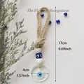 Handgefertigter Evil Eye Wandbehang mit Webseil, weißen Perlen und blauem Anhänger - Transparent