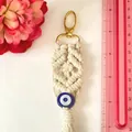 Detailed macro view of handmade macrame evil eye keychain with cotton fringe and gold clasp - Cotton Blue Eye Small Pendant