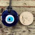 Gros plan du pendentif Oeil du Mal de 3,5 cm avec une pièce pour comparer la taille - Style Rond / 3.5cm