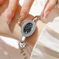 Detailed close-up of oval quartz watch with rhinestone bezel on a woman's wrist - Silver Black
