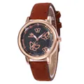 Gros plan d'une montre en or rose avec cadran papillon étoilé et bracelet en daim marron - Marron