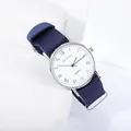 Détail d'une montre à quartz avec chiffres romains, cadran blanc et bracelet en nylon bleu - Cadran Blanc Bracelet Bleu