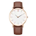 Detail of minimalist watch with rose gold case, white dial, and brown leather strap - Brown