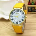 Detalle de reloj dorado con esfera de nácar, números negros y correa de cuero amarillo - Amarillo