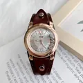 Détail du cadran doré rose avec chiffres romains et strass mobiles sur bracelet en cuir - Brun Texturé