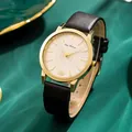 Close-up of golden quartz watch with lotus detail and black leather strap on green silk - Black