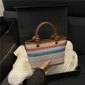 Colorful woven straw handbag with brown leather knot handles and striped texture - Brown