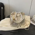 Elegant ivory pearl bucket bag featuring floral embroidery and a gold chain strap - White Floral