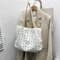 White quilted tote bag with black bow embroidery and rope strap in a variant view - White