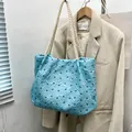 Light blue quilted bow tote bag with cream rope straps hanging on a wooden hanger - Blue
