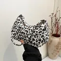 Fashionable underarm bag featuring a classic leopard print and sleek curved structure - White Leopard