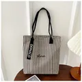 Close-up of striped canvas tote bag with Humor embroidery and Donald ribbon tag detail - Black