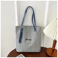 Detail of blue striped canvas tote bag with Humin embroidery on a wooden table - Blue