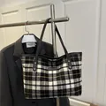 Plaid tweed tote bag with yellow accents and black leather straps hanging on a rack - Large Black Plaid