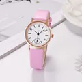 Women's pink leather quartz watch with gold case and floral dial pattern on white desk - Pink
