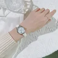 Detail of silver cat-ear quartz watch with white leather strap on female wrist - White