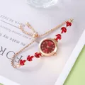 Detail of adjustable gold bracelet watch featuring red leaf crystals and red quartz dial - Red