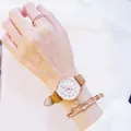 Detail of rose gold watch with heart dial and matching star charm bracelet on wrist - Brown Watch + Bracelet