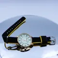 Detailed view of casual quartz watch with gold case and striped nylon NATO strap on mirror - Black