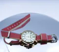 Close-up of luminous quartz watch with rose gold case and striped NATO nylon strap - Orange Red