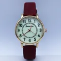 Detailed macro view of gold quartz watch case with green dial and red textured strap - Red