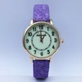 Detail view of the purple denim texture strap and gold case of this quartz watch - Purple