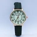 Macro detail of quartz watch with rose gold case and dark green fabric strap - Green
