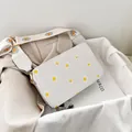 Detailed macro view of white daisy print on canvas crossbody bag with gold metal hardware - White