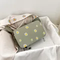 Detail of pea green crossbody bag with daisy prints and wide canvas shoulder strap - Green