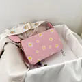 Detail view of pink PU leather crossbody bag with daisy prints and gold metal hardware - Pink