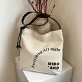 Naturweiße Canvas-Beuteltasche mit schwarzen Lederriemen und stilvollem Textaufdruck - Stil 2