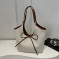 Beige woven tote bag with brown leather handles and a decorative bow accent - Brown
