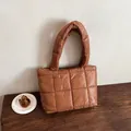 Borsa tote trapuntata marrone con grandi cuciture quadrate su un tavolo di legno - Marrone