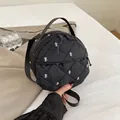 Chic black round quilted crossbody bag featuring elegant white bow embroidery details - Black