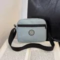 Light blue nylon crossbody bag with SPORT logo resting on an open book in a casual setting - Blue