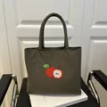 Olive green canvas tote bag featuring red apple embroidery and padded handles - Green