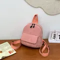 Detalle de mini mochila de pana rosa sobre mesa de madera con cremallera doble y bolsillo - Rosa