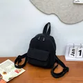 Detalle de una mini mochila de pana negra con textura de rayas finas y bolsillo frontal - Negro