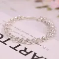 Dettaglio del bracciale d'argento a forma di cuore con zirconi su carta bianca elegante - Bracciale d'Argento