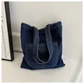 Detail shot of navy denim tote bag featuring contrast stitching and large front pocket - Dark Blue