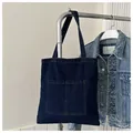 Detail of dark denim tote bag featuring dual front utility pockets and sturdy shoulder straps - Dark Blue