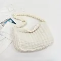 Macro shot of white pleated cloud bag texture and ruffled fabric detail on shoulder strap - White