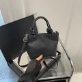Schwarze Bucket Bag mit Lychee-Muster, Knotengriff und goldenen Metallteilen - Schwarz