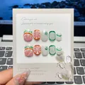 Detalle de uñas postizas hechas a mano con diseños de pomelo y lima pintados con realismo - L
