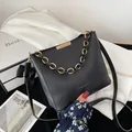 Dettaglio della borsa a secchiello in pelle nera con catena d'oro e scritta - Nero