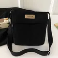 Compact black corduroy crossbody bag featuring a fashion label and adjustable strap - Black