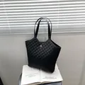 Bolso tote acolchado negro con patrón de diamantes y logo de flor dorada sobre fondo claro - Negro